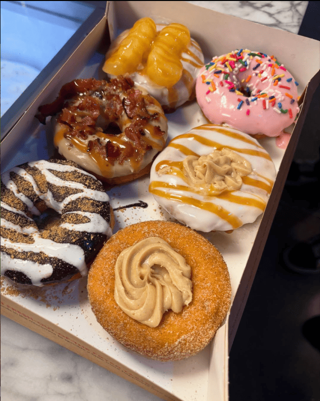 A vibrant display of donuts, desserts, ice cream, and coffee for catering or in-store breakfast at Duck Donuts.