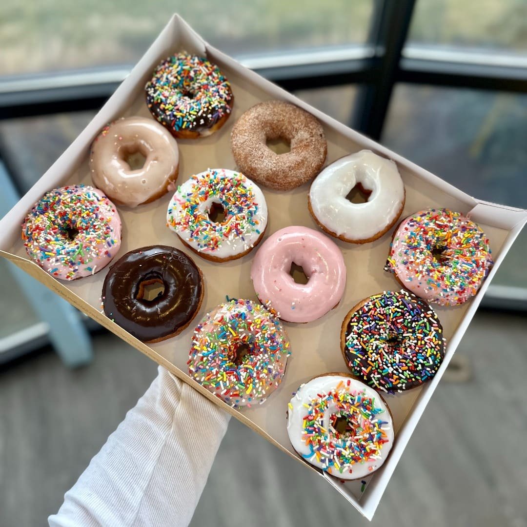 Staff serving custom donuts and desserts alongside coffee and breakfast treats at Duck Donuts.