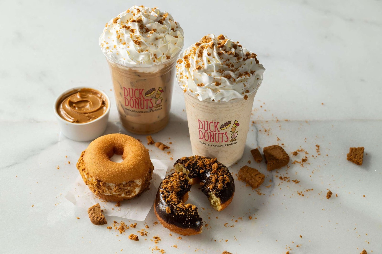 Colorful donuts with dessert toppings and coffee cups on display for breakfast and catering at Duck Donuts.