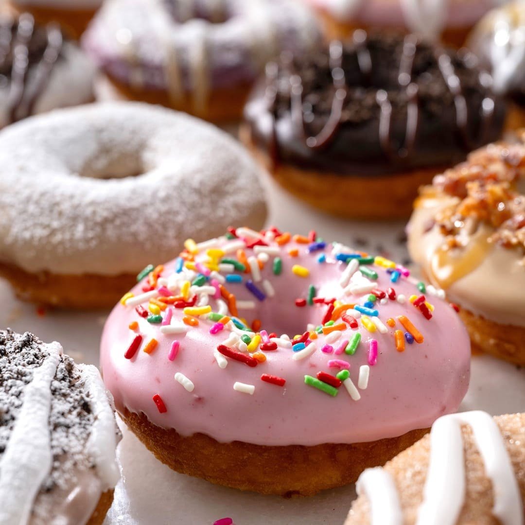 A table of vegetarian-friendly donuts and desserts with coffee and ice cream at Duck Donuts.